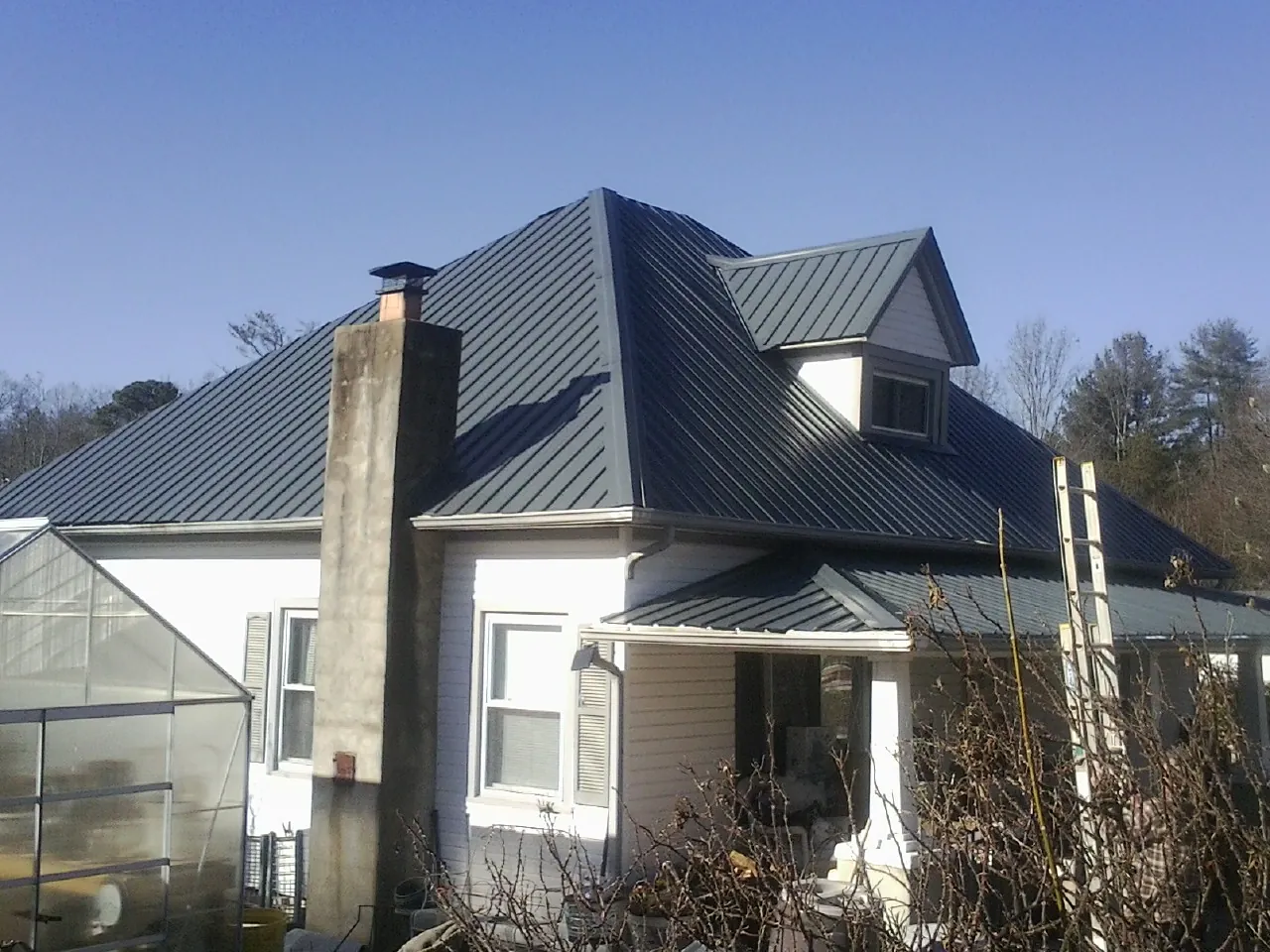 Dark blue standing seam metal roof on a white farmhouse with dormer — Slate & Tile Roof Repair by Roofing Brothers in Blacklick
