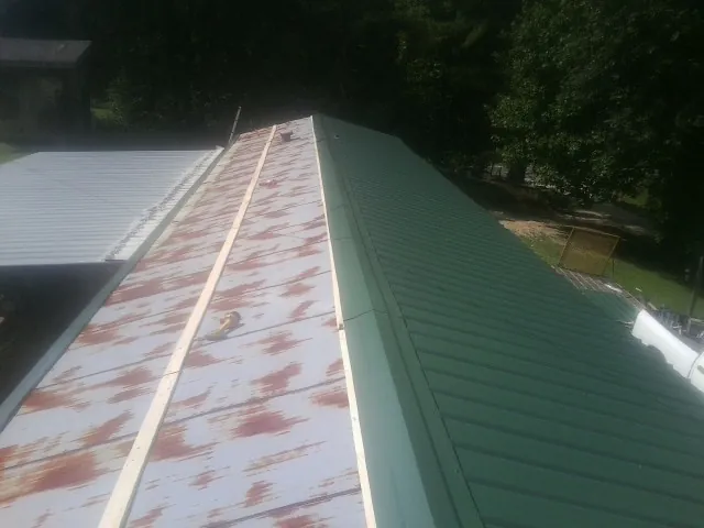Old rusted panels beside newly installed green metal roofing — Wind Damage Roof Repair by Roofing Brothers in Blacklick