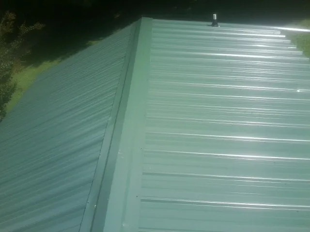 New green metal panels meeting at the ridge of a roof — Flat Roof Repair work by our crew in Blacklick