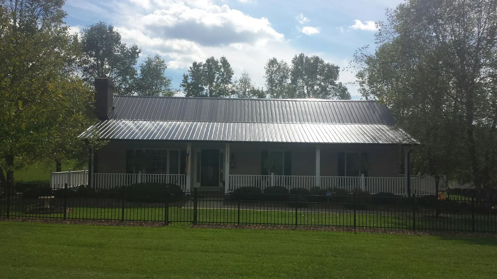 Gray metal roof on a brick ranch with a full width front porch — Gutter Guard Installation work by our crew in Blacklick