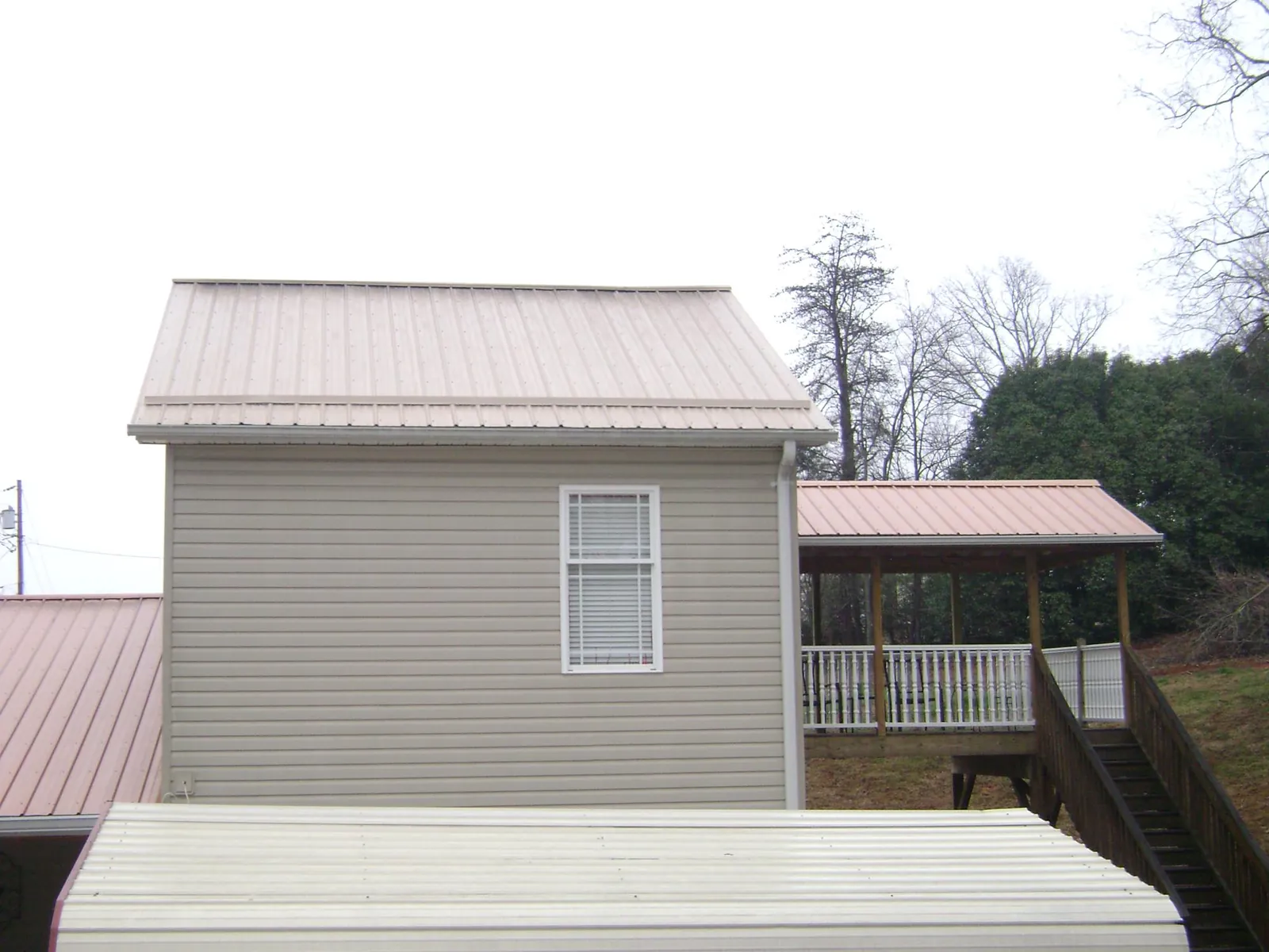 Tan metal roofs on a two story addition and attached porch, from a Roof Replacement job in Blacklick