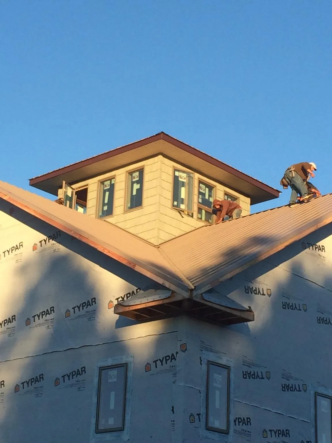 Roofers working around a rooftop cupola on a new metal roof at sunset — Roof Waterproofing in Blacklick by Roofing Brothers